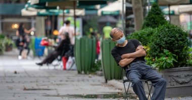 A man wearing a mask takes a nap while sitting in Bryant Park in New York City, U.S., Aug. 7, 2020. (Getty Images)