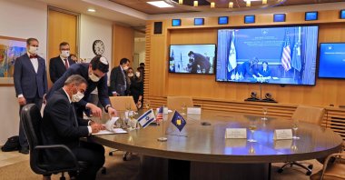 Israel's Foreign Minister Gabi Ashkenazi (L), mask-clad due to the COVID-19 coronavirus pandemic, signs a joint declaration establishing ties with Kosovo during an official ceremony held over Zoom with his counterpart from Kosovo Meliza Haradinaj Stublla (screen), at the Israeli Foreign Ministry headquarters in Jerusalem on Feb. 1, 2021. (AFP Photo)