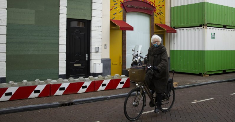 A woman cycles past luxury goods stores that are boarded up, protected by concrete blocks and sea containers at P.C. Hooft street in Amsterdam, the Netherlands, Friday, Jan. 29, 2021. (AP Photo)