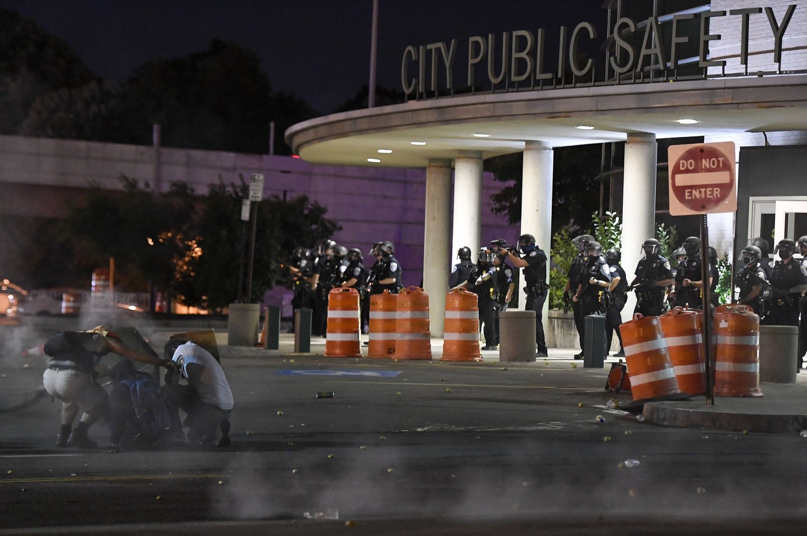 Demonstrators take cover from chemical irritants released by police in front of the Public Safety Building in Rochester, New York, U.S., Sept. 3, 2020. (AP Photo)