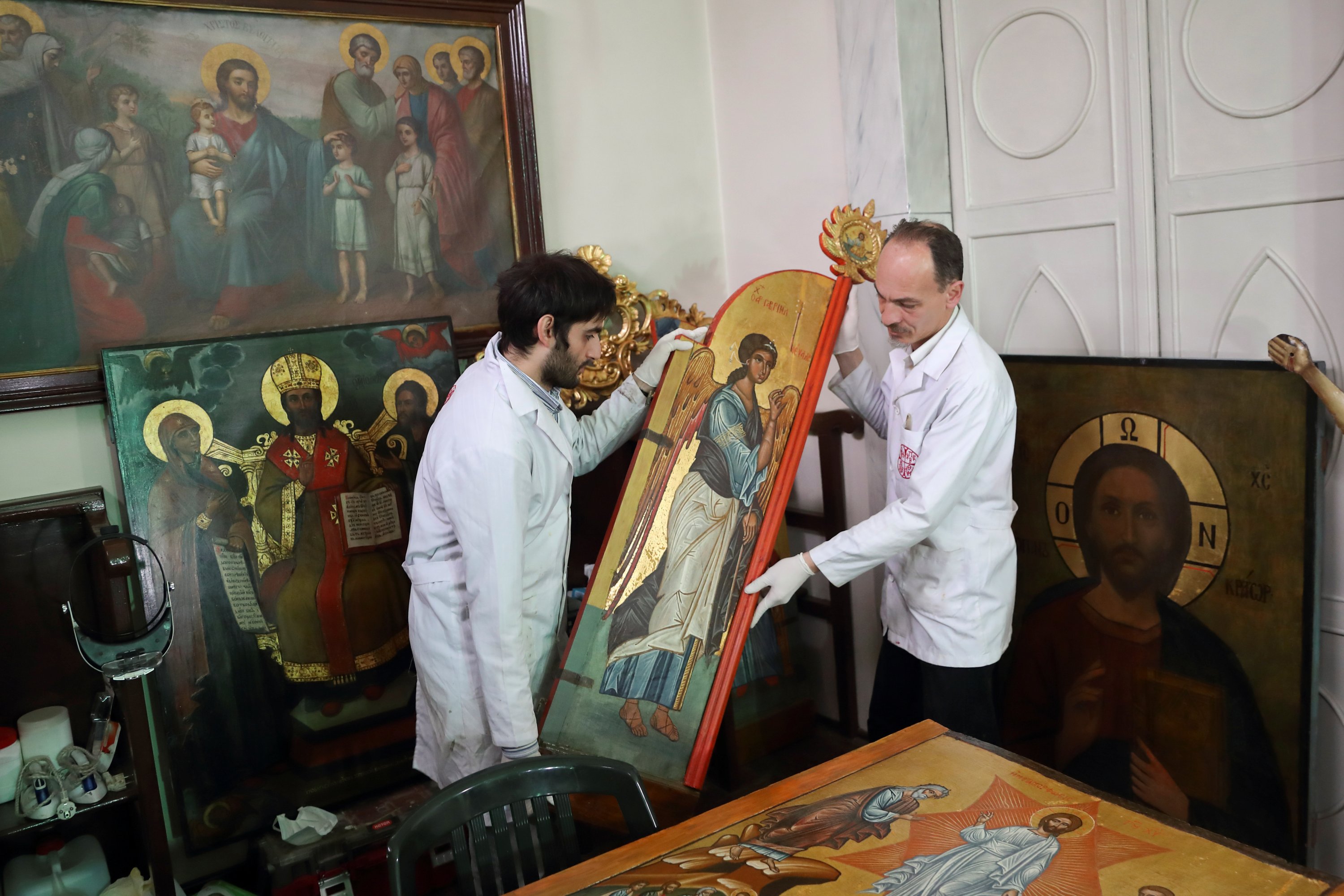  Venizelos Gavrilakis (R) and his assistant Umut Ballıkaya carry an early 17th-century royal door after they completed cleaning and restoration work on it at a Greek Orthodox church where Gavrilakis set up his laboratory in Istanbul, Turkey, Jan. 26, 2021. (Reuters photo)