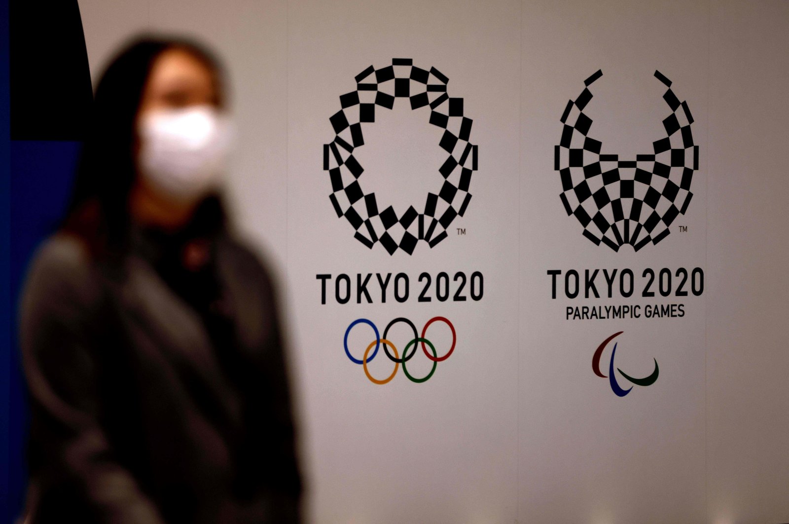 A woman wearing a face mask walks past Tokyo 2020 Olympic and Paralympic Games' logos in Tokyo, Japan, Feb. 2, 2021. (AFP Photo)