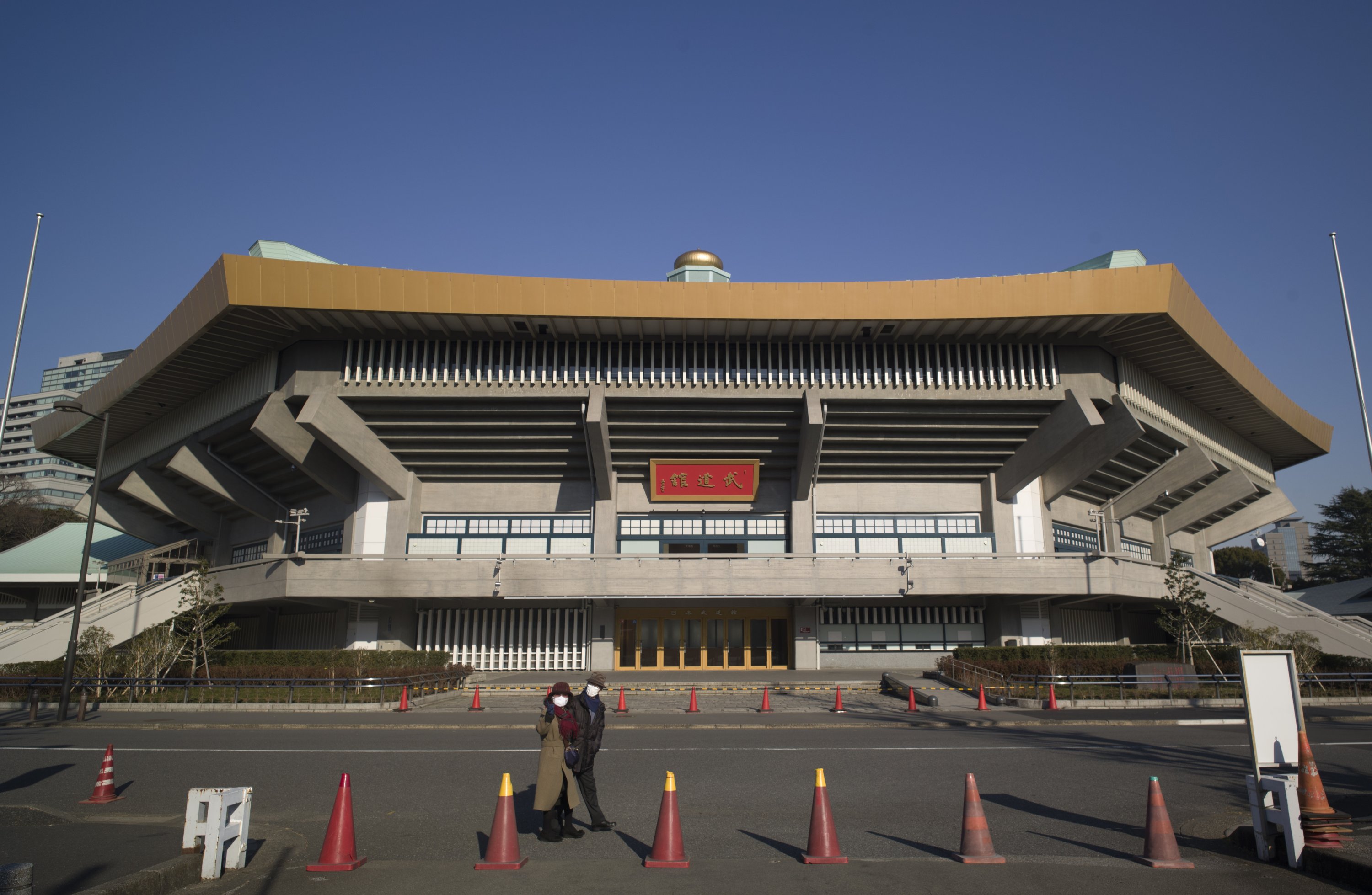 A man and a woman walk past the Nippon Budokan arena, one of the venues planned to be used in the rescheduled Tokyo Olympics, in Tokyo, Japan, Jan. 21, 2021. (AP Photo)