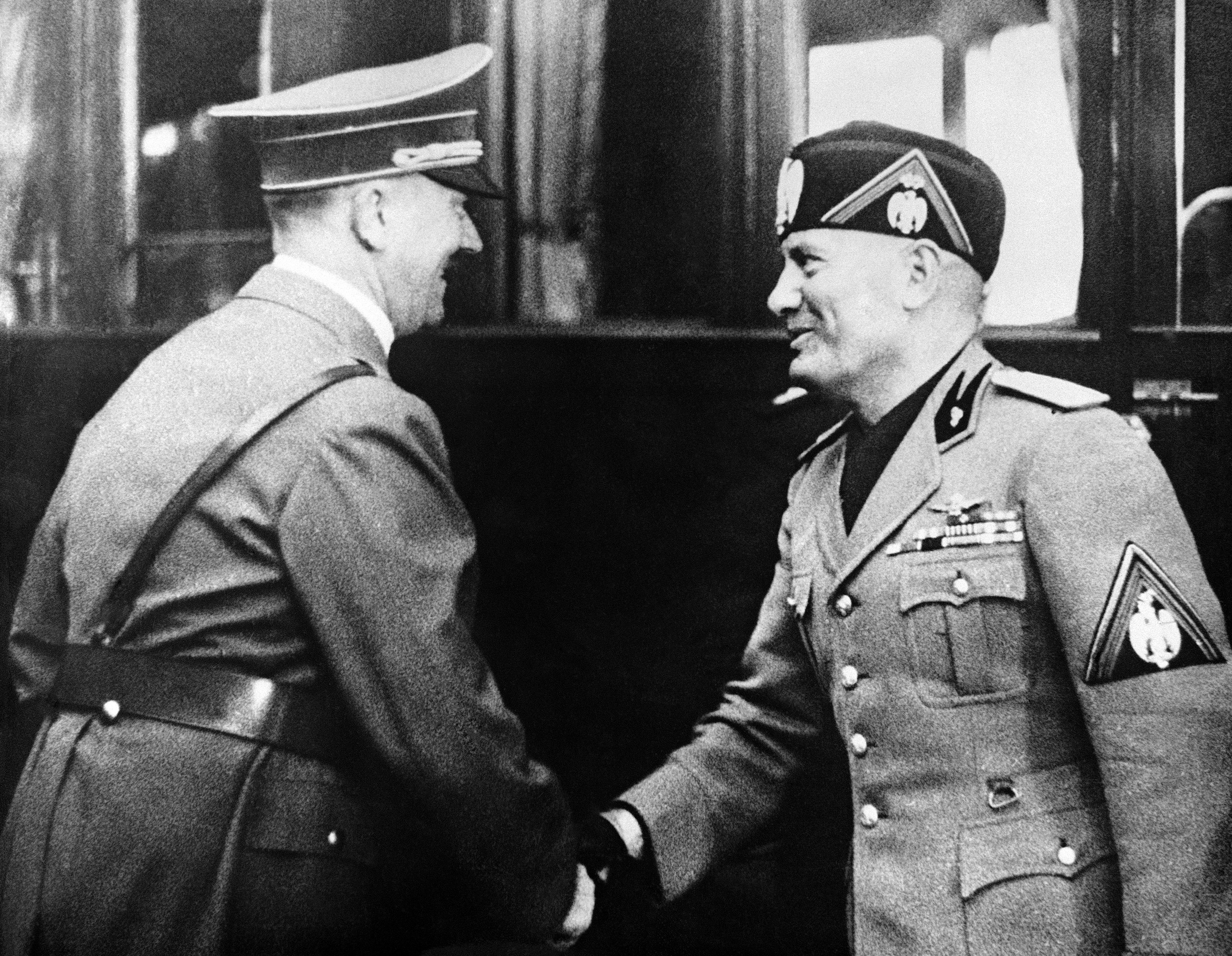 German Chancellor Adolf Hitler (L) greeting Italian dictator Benito Mussolini on his arrival after watching German Army maneuvers at Mecklenburg and visiting the famous Krupp armament factory, in Essen, Germany, Sept. 27, 1937. (AP Photo)