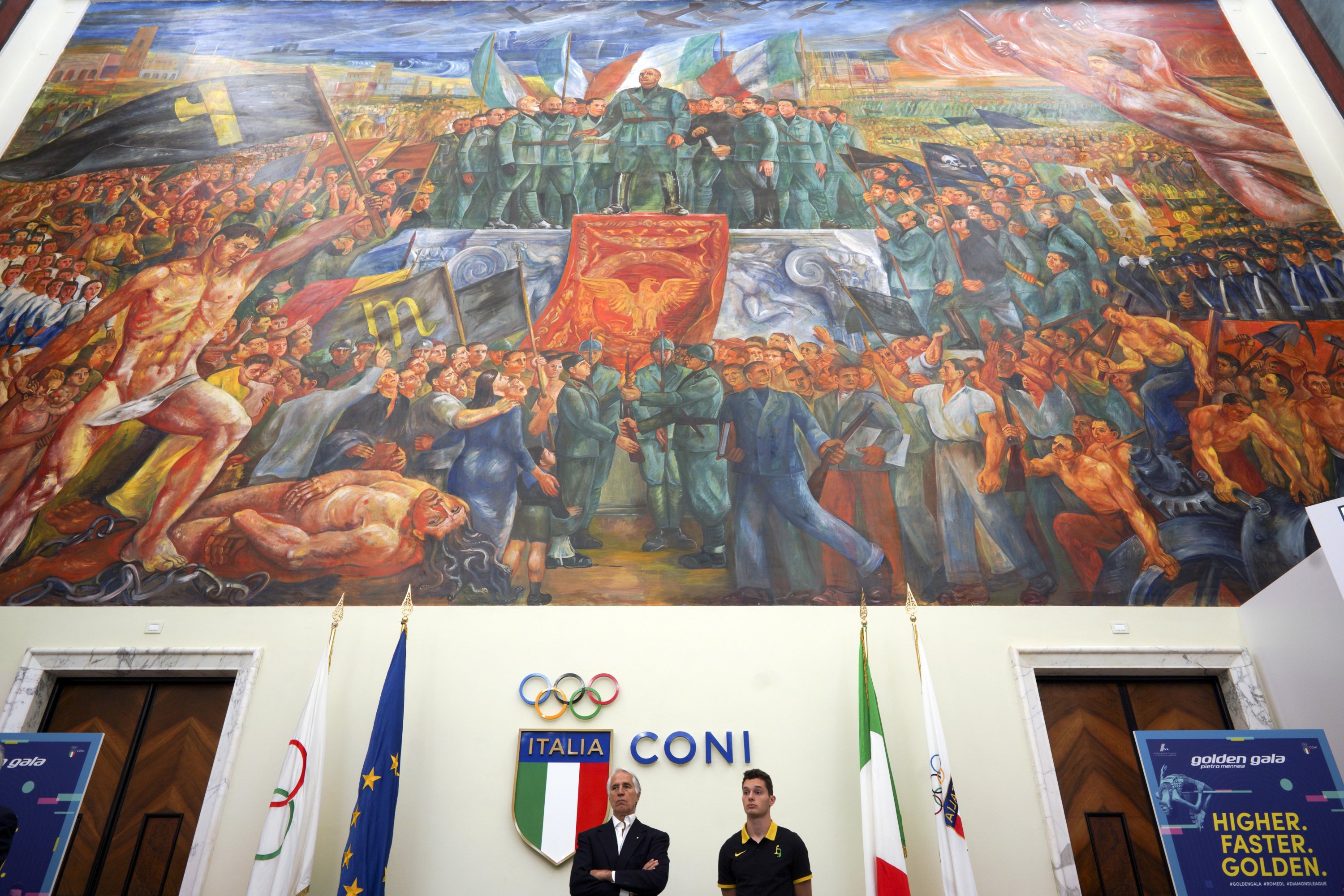 CONI (Italian Olympic Committee) president Giovanni Malago (bottom L) and Italian athlete Filippo Tortu attend a press conference to present the Golden Gala athletic meeting, as they stand beneath a mural titled "Apotheosis of Fascism," in the Salone d