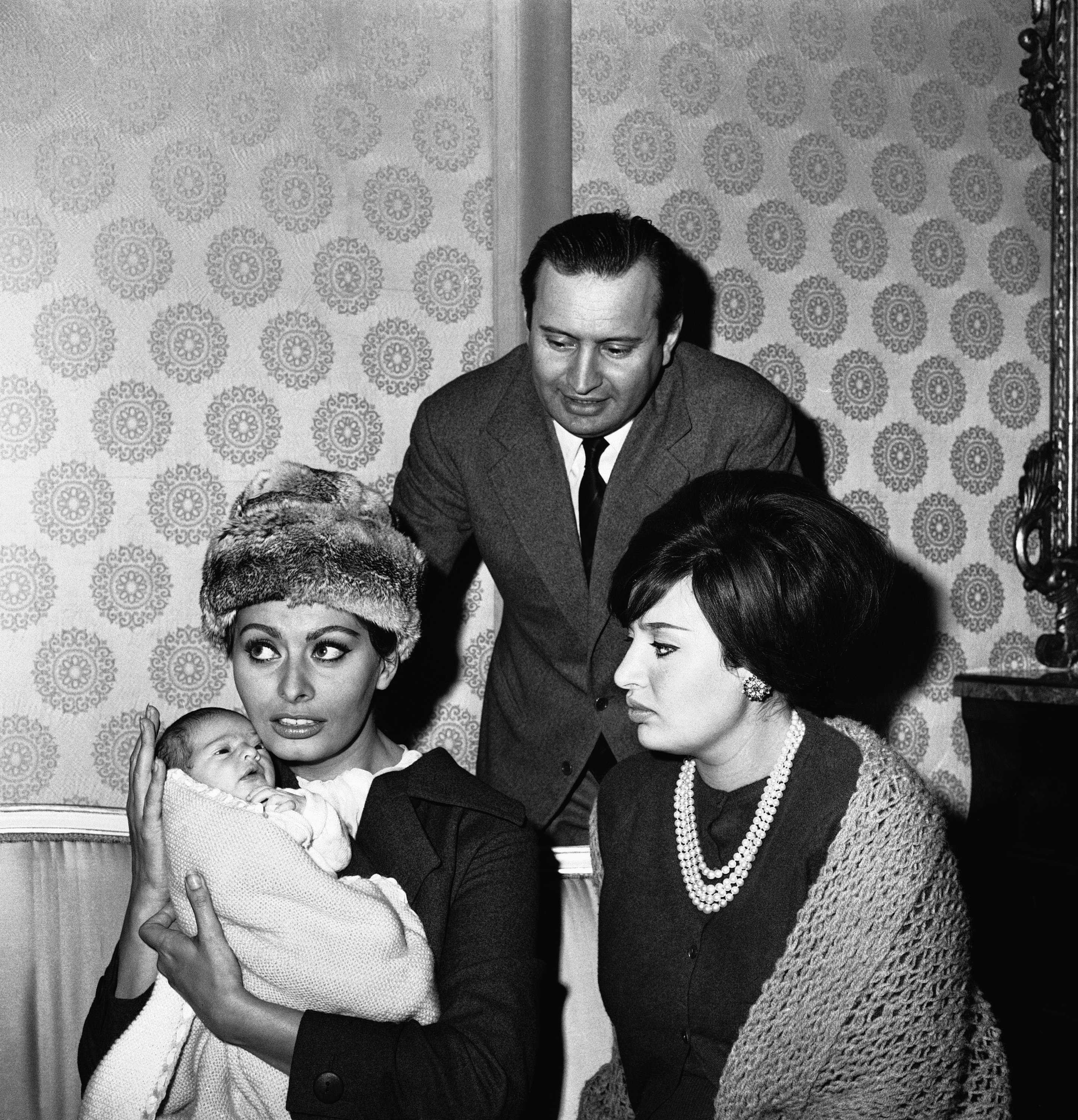 Italian actress Sophia Loren (L) holds her niece, 12-day old Alessandra, during a picture-taking session in the apartment of the child’s parents, Romano Mussolini (C), youngest son of dictator Benito Mussolini, and Sophia’s sister Maria, in Rome, Italy, Jan. 11, 1963. (AP Photo)
