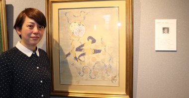 Japanese illuminator Fumiko Takahor poses with her work illustrating the name of the Prophet Muhammad in Arabic letters together with a rose motif at Yunus Emre Institute, Tokyo, Japan, Feb. 3, 2020. (AA Photo)