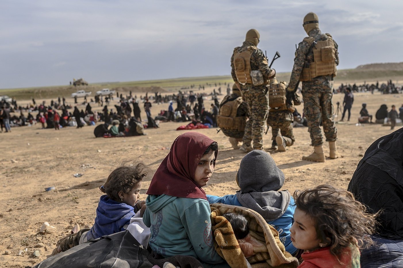 Civilians evacuated from the Daesh terrorist group's embattled holdout of Baghouz wait at a screening area held by the YPG terrorist group, in the northeastern Syrian province of Deir el-Zour, March 5, 2019. (AFP Photo)