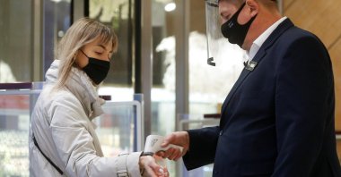 An employee wearing a mask and face shield checks the body temperature of a visitor at the Central Universal Department Store (TsUM), on the first day after ending a coronavirus lockdown, in Kyiv, Ukraine, Jan. 25, 2021. (Reuters Photo)