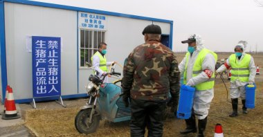 Workers in protective suits disinfect a vehicle at a checkpoint, leading to a farm owned by Hebei Dawu Group where African swine fever was detected, in the Xushui district of Baoding, Hebei province, China, Feb. 26, 2019. (REUTERS Photo)