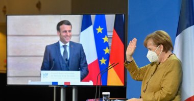 French President Emmanuel Macron (L) seemingly watches German Chancellor Angela Merkel wave at the end of a press conference after German-French Security Council video talks, Berlin, Germany, Feb. 5, 2021. (AFP Photo)