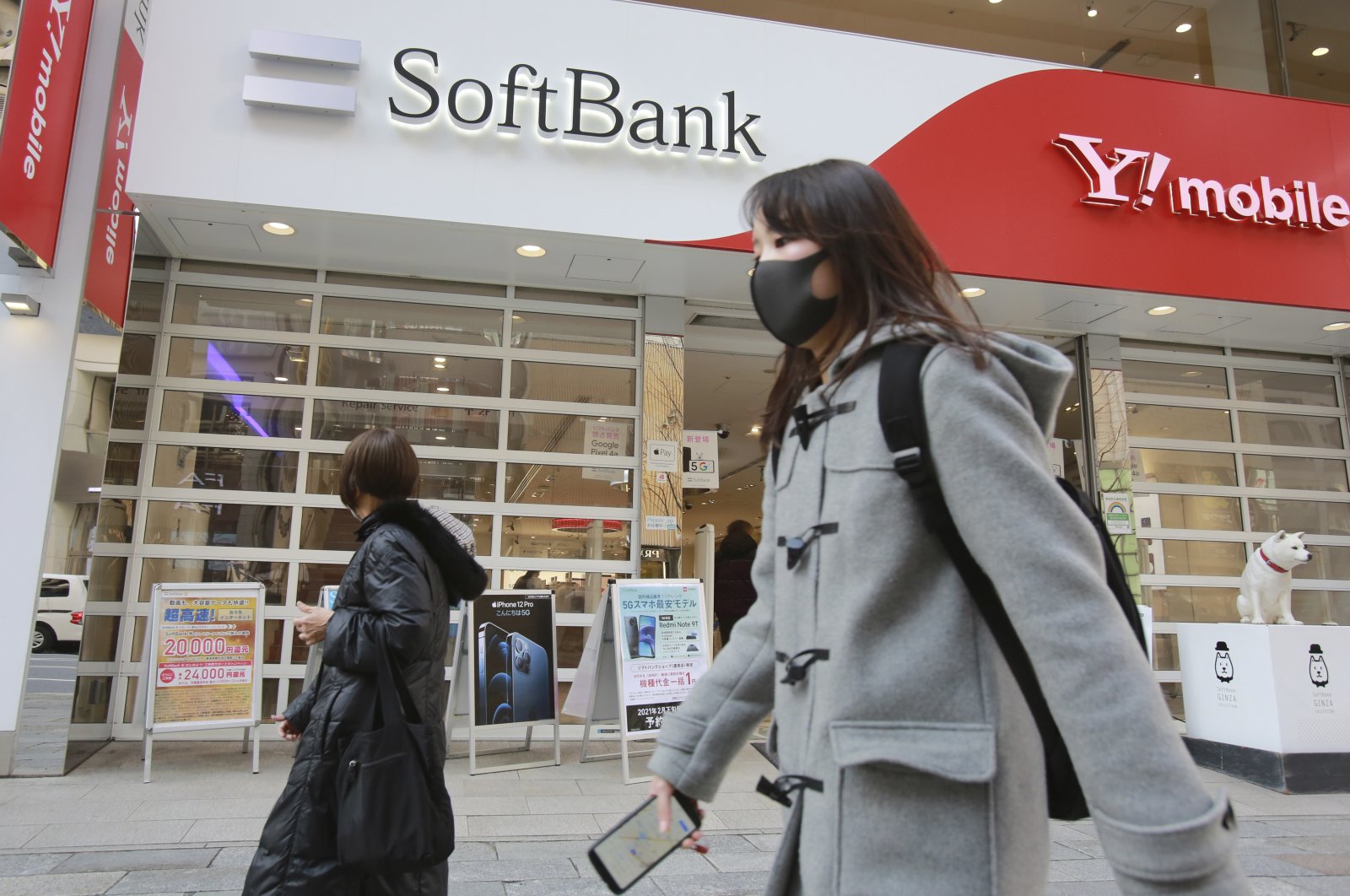 People walk by a SoftBank shop in Tokyo, Japan, Feb. 8, 2021. (AP Photo)