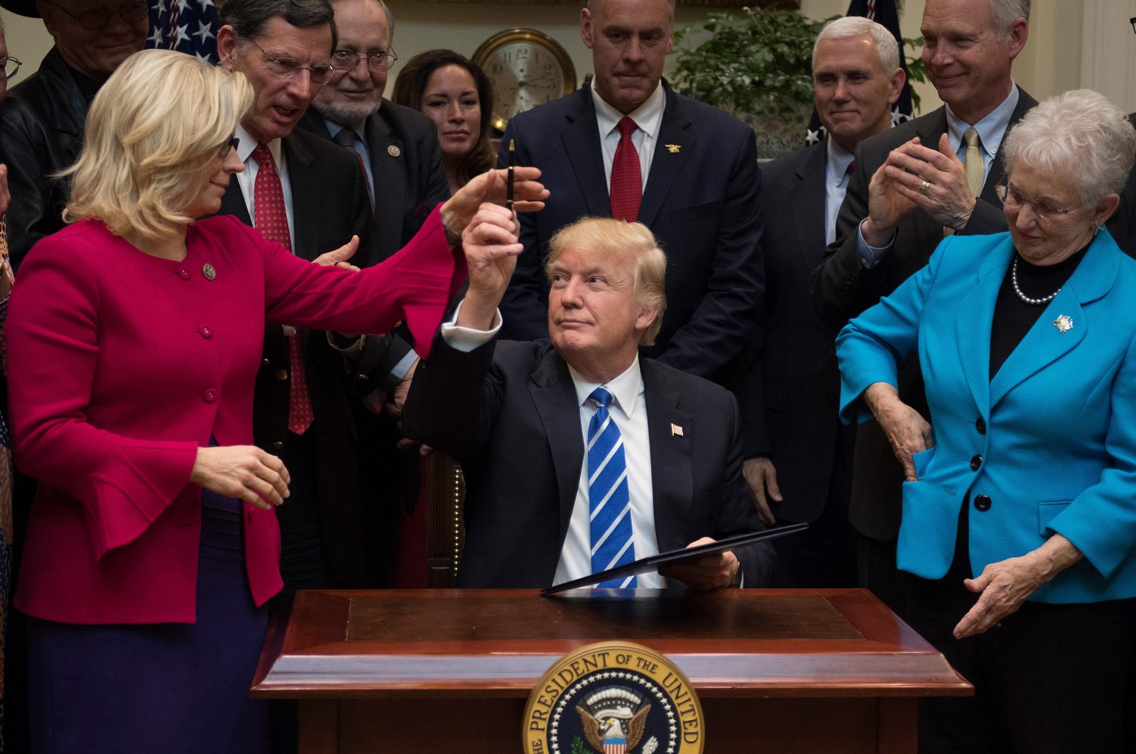 U.S. President Donald Trump gives a pen to U.S. Congressperson Liz Cheney (L), R-Wyoming, after signing H.J. Resolution 37, 44, 57 and 58 at the White House in Washington, DC., U.S. March 27, 2017. (AFP Photo)