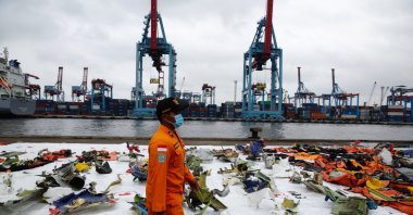 A member of Indonesia's National Search and Rescue Agency (BASARNAS) walks past the debris of Sriwijaya Air flight SJ 182 plane recovered from the crash site in the waters off Jakarta at Tanjung Priok port in Jakarta, Indonesia, Jan. 17, 2021. (EPA Photo)