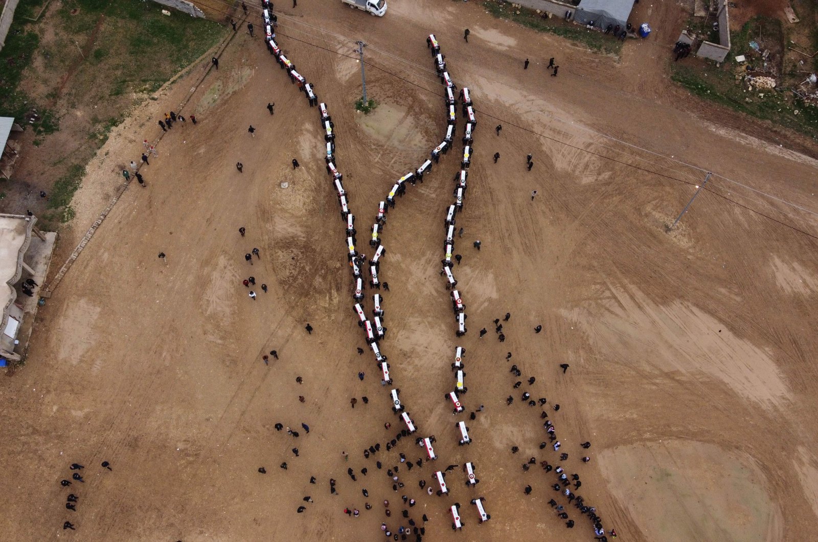 An aerial picture shows mourners carrying coffins wrapped in the Iraqi flag in a procession during a mass funeral for Yazidi victims of Daesh in the northern Iraqi village of Kojo in Sinjar district, on Feb. 6, 2021. (AFP Photo)