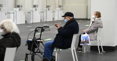 An elderly man checks a smartphone while waiting at a COVID-19 vaccination center to receive a vaccine in Cologne, western Germany, Feb. 8, 2021. (AFP Photo)