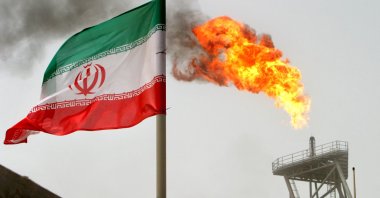 A gas flare on an oil production platform in the Soroush oil fields is seen alongside an Iranian flag in the Persian Gulf, Iran, July 25, 2005. (Reuters Photo)