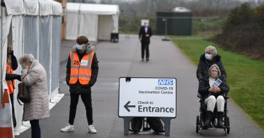 Volunteers assist a woman (L) as people who received a COVID-19 vaccine leave a temporary vaccination hub set up at the Colchester Community Stadium in Colchester, Essex, southeast England, Feb. 6, 2021. (AFP Photo)