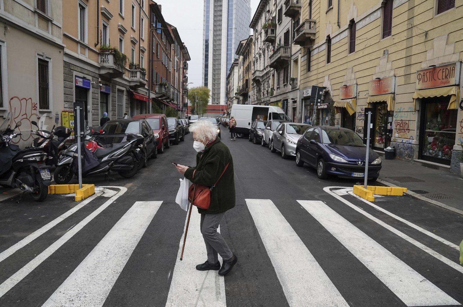 An elderly woman crosses a street in Milan, Italy, Dec. 1, 2020. (AP Photo)