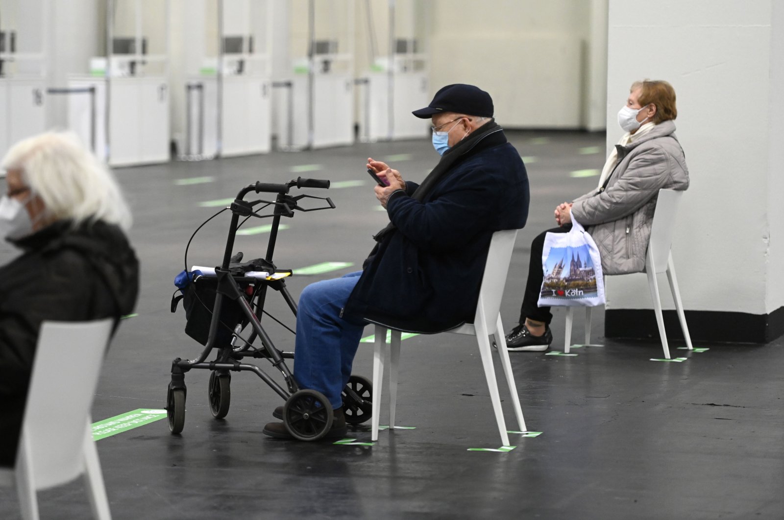 An elderly man checks a smartphone while waiting at a COVID-19 vaccination center to receive a vaccine in Cologne, western Germany, Feb. 8, 2021. (AFP Photo)