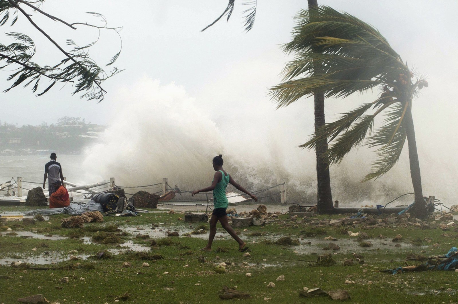 Local residents walk past debris as a wave breaks nearby in Port Vila, the capital city of the Pacific island nation of Vanuatu March 14, 2015. (UNICEF Pacific via Reuters)