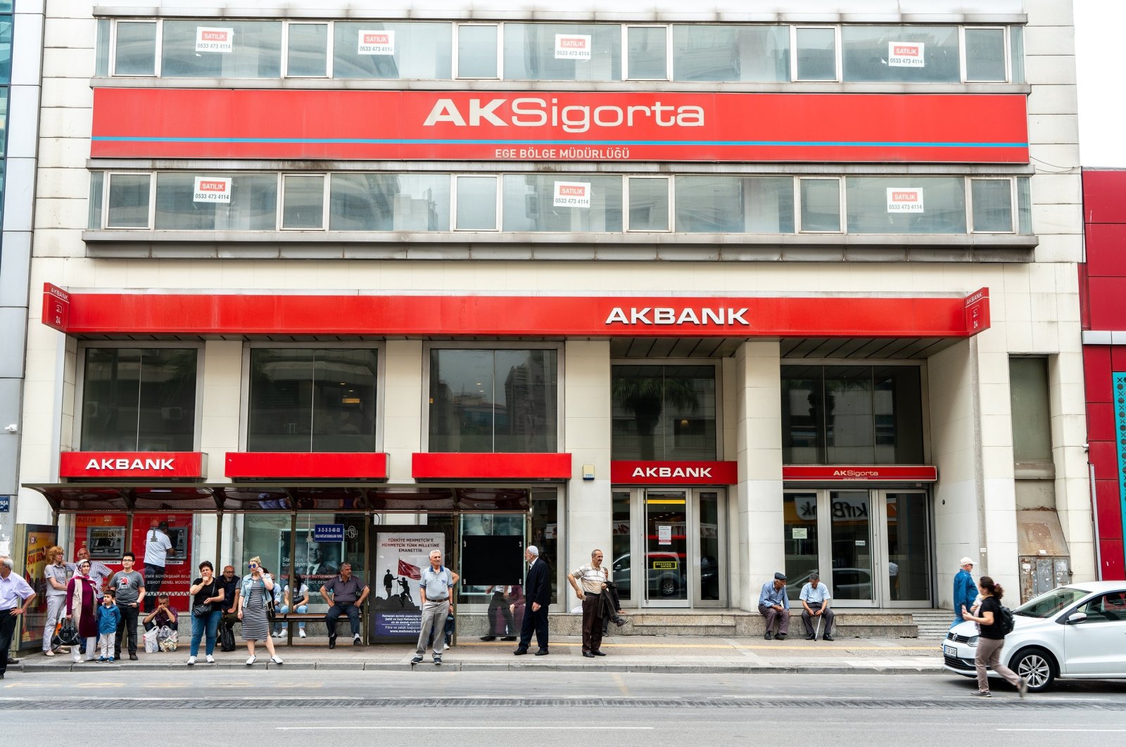 An Akbank branch is seen as people walk by and wait at a bus stop, Izmir, western Turkey, May 19, 2019. (Shutterstock Photo)