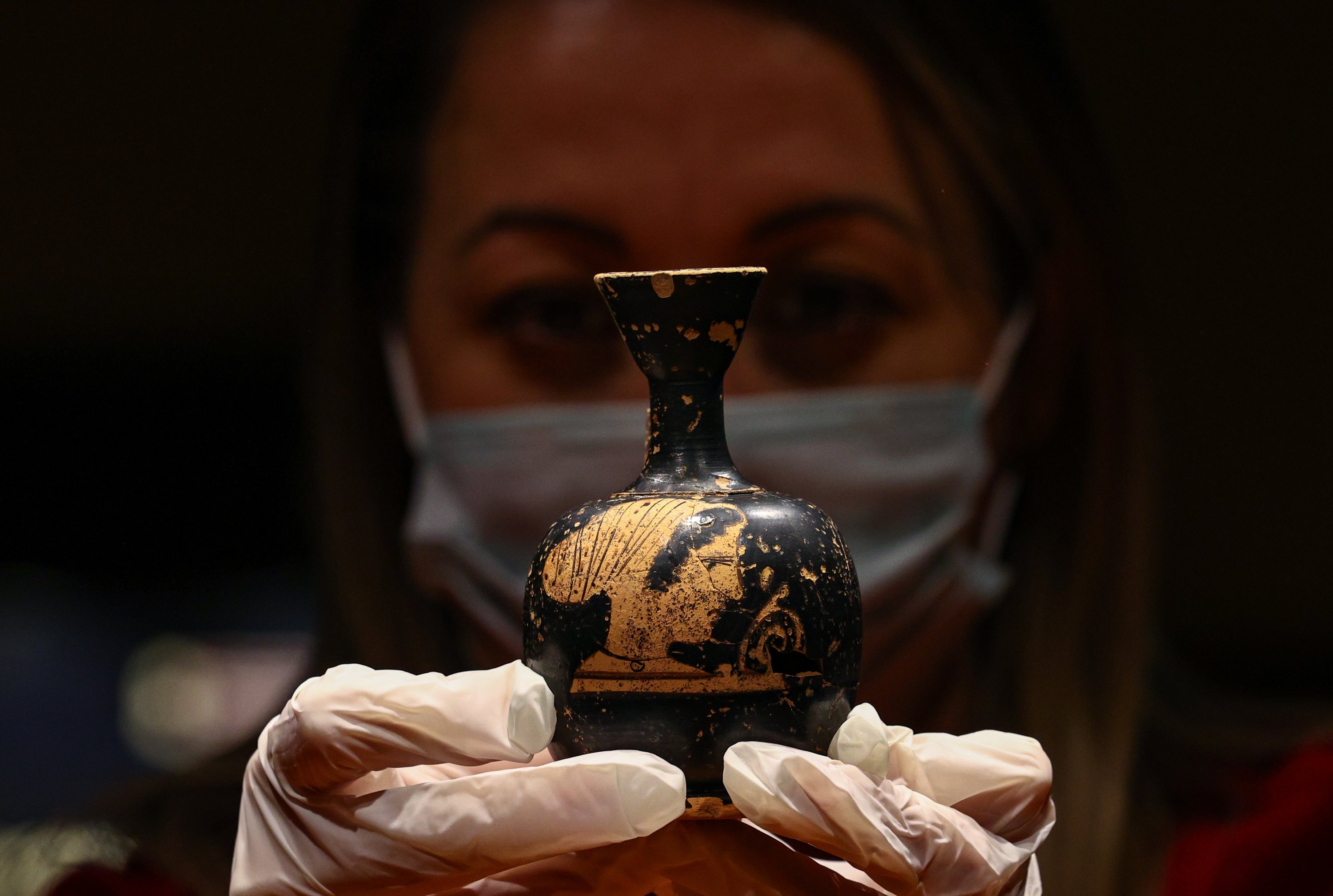 An attendant holds an ancient perfume bottle at the Izmir Archaeological Museum, Izmir, western Turkey, Feb. 11, 2021. (AA Photo)