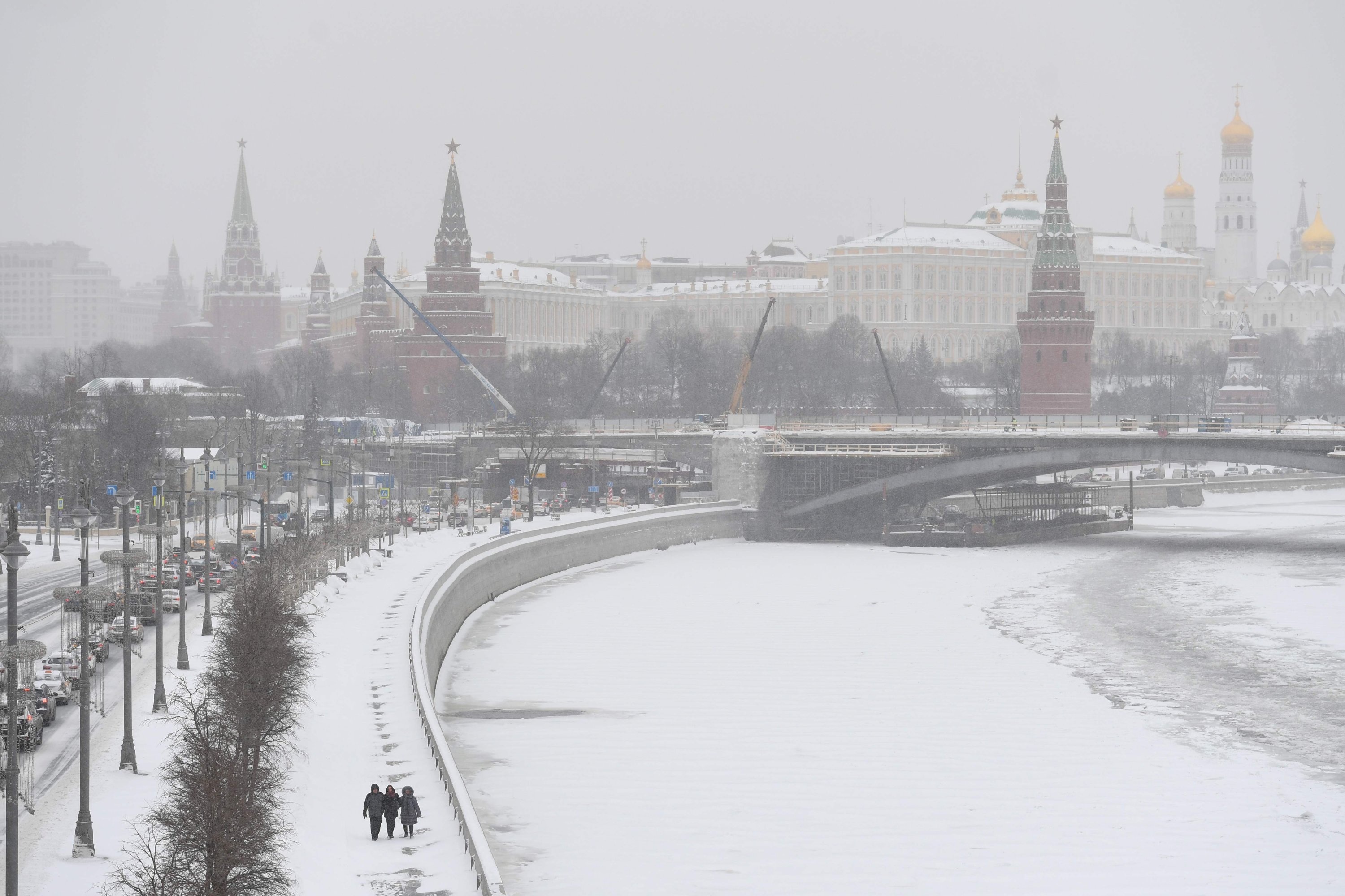 People walk along an embankment of the Moskva River with the Kremlin in the background during a heavy snowfall in Moscow on Feb. 12, 2021. (AFP Photo)