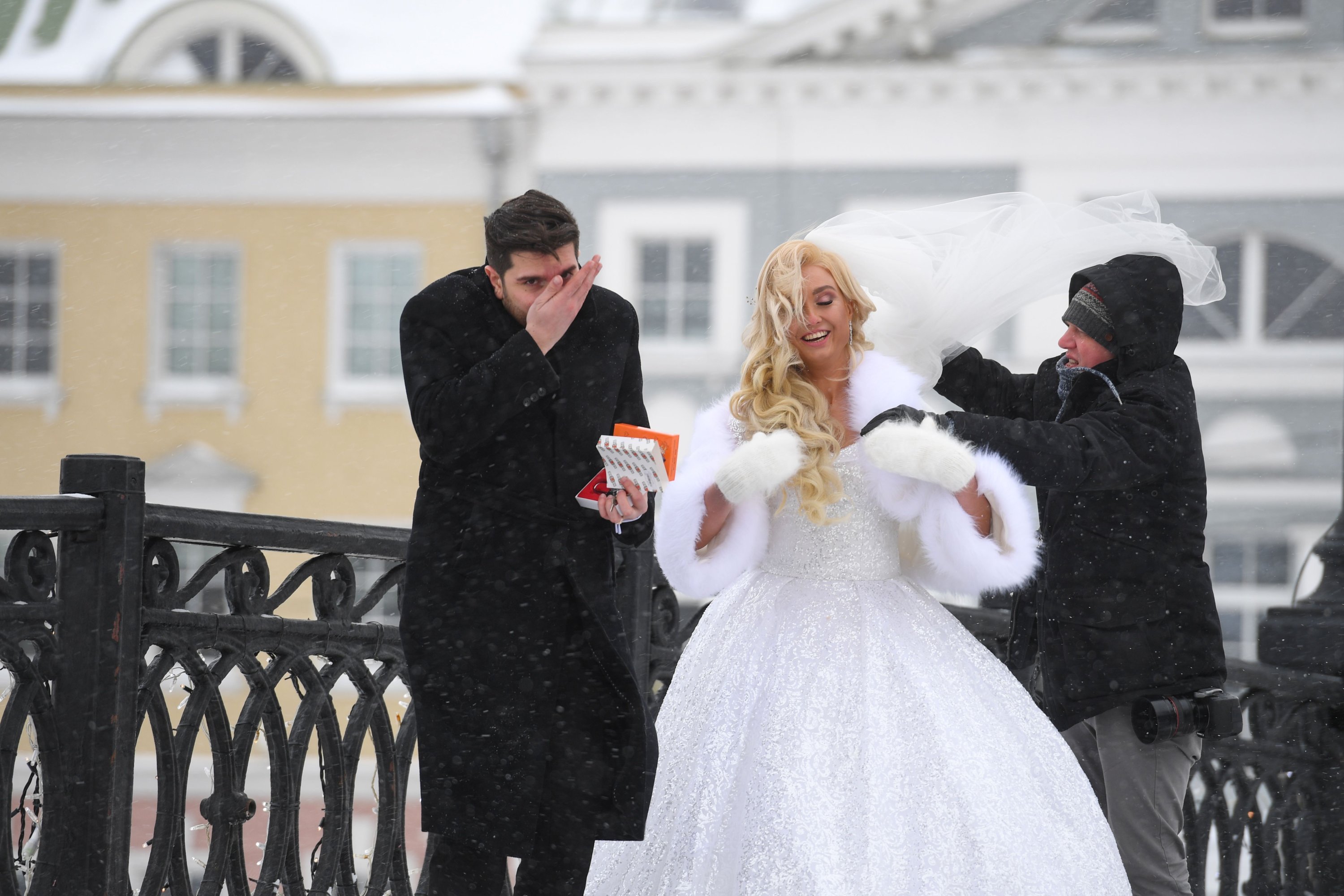 A photographer adjusts the wedding dress of a bride during a photo session on a snowy day in Moscow on Feb. 12, 2021. (AFP Photo)