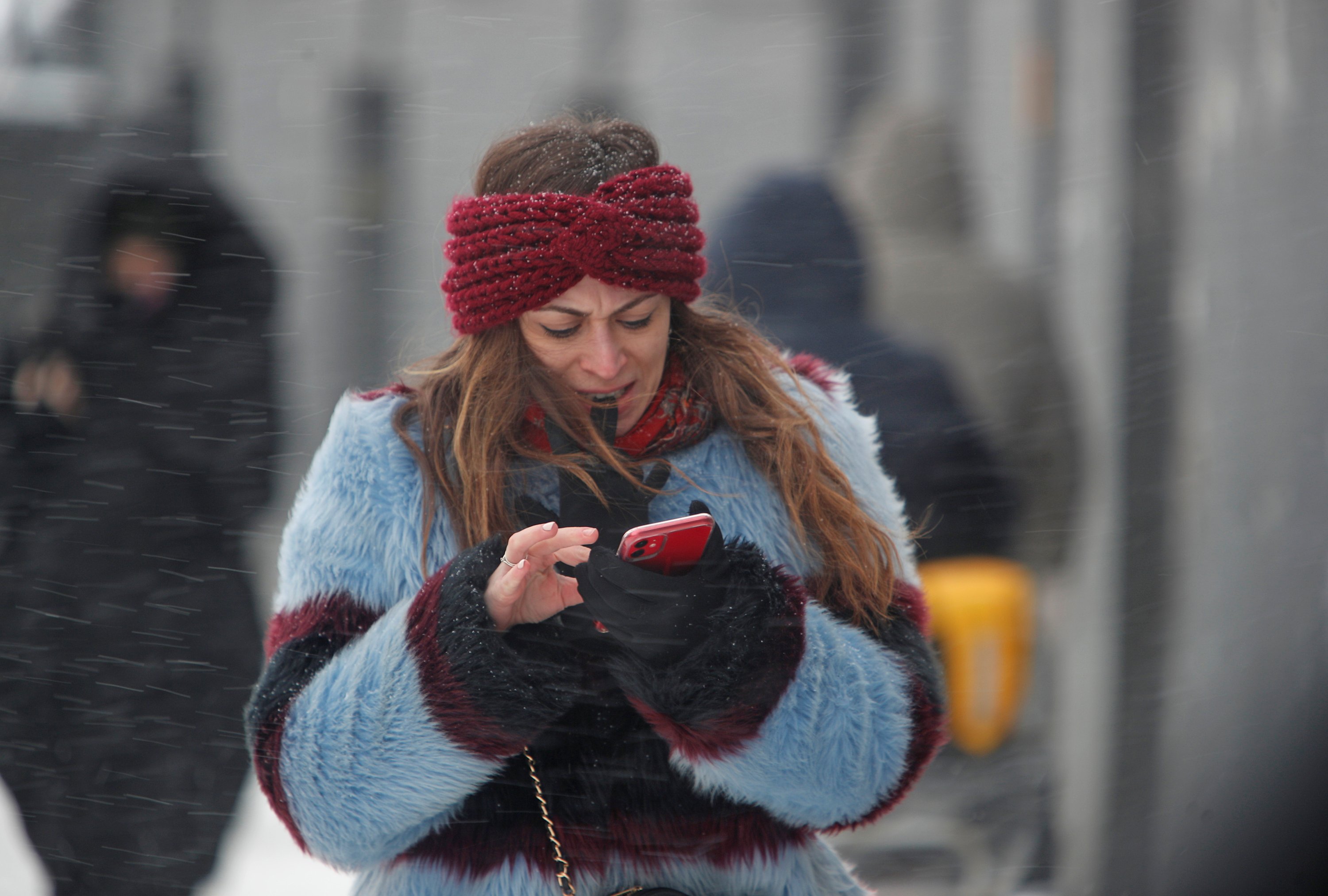 A woman uses a smartphone as she walks along a street during heavy snowfall in Moscow, Russia on Feb. 12, 2021. (Reuters Photo)
