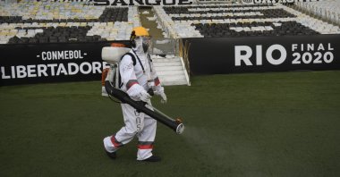 A worker wearing protective gear disinfects the pitch as a precaution against the coronavirus during the half break of a Copa Libertadores final soccer match between Brazil's Palmeiras and Brazil's Santos at the Maracana stadium in Rio de Janeiro, Brazil, Jan. 30, 2021. (AP Photo)