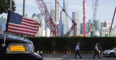 Chinese police officers walk by a U.S. flag on an embassy car outside a hotel in Shanghai, China, July 30, 2019. (AP Photo)