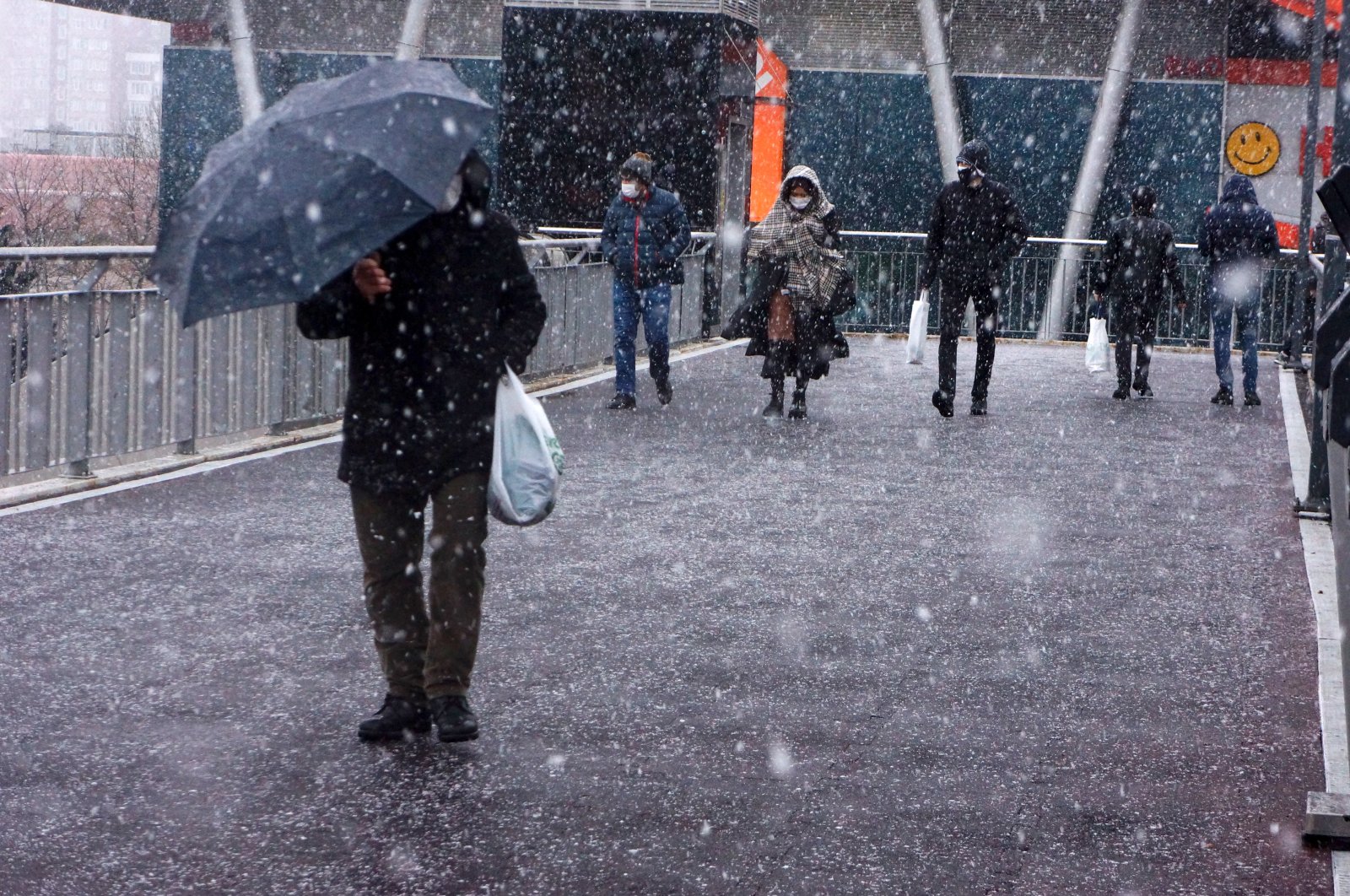 People walk as snow falls in the Beylikdüzü district of Istanbul, Turkey, Feb. 12, 2021. (AA PHOTO)