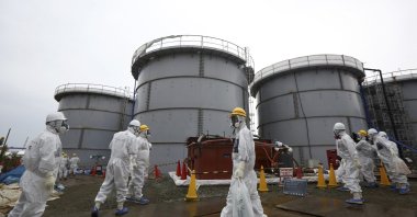 Members of the media and Tokyo Electric Power Co. (TEPCO) employees wearing protective suits and masks walk past storage tanks for radioactive water in the H4 area at the tsunami-crippled TEPCO Fukushima Daiichi nuclear power plant in Fukushima prefecture, Nov. 7, 2013. (Reuters Photo)
