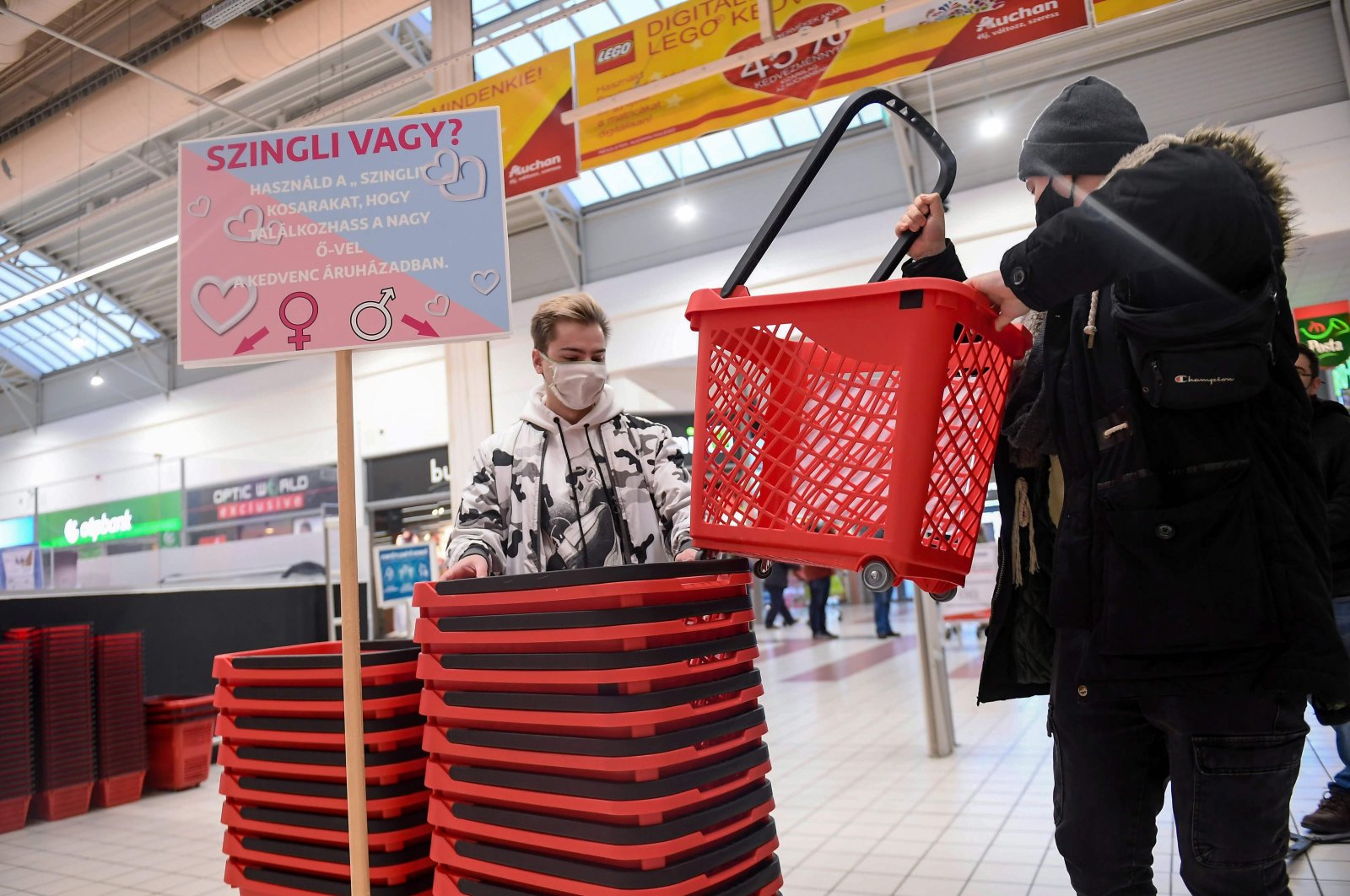 Two young men pick up their "single" shopping baskets at a French Auchan supermarket in Csomor town, Hungary, on Feb. 12, 202 (AFP Photo)