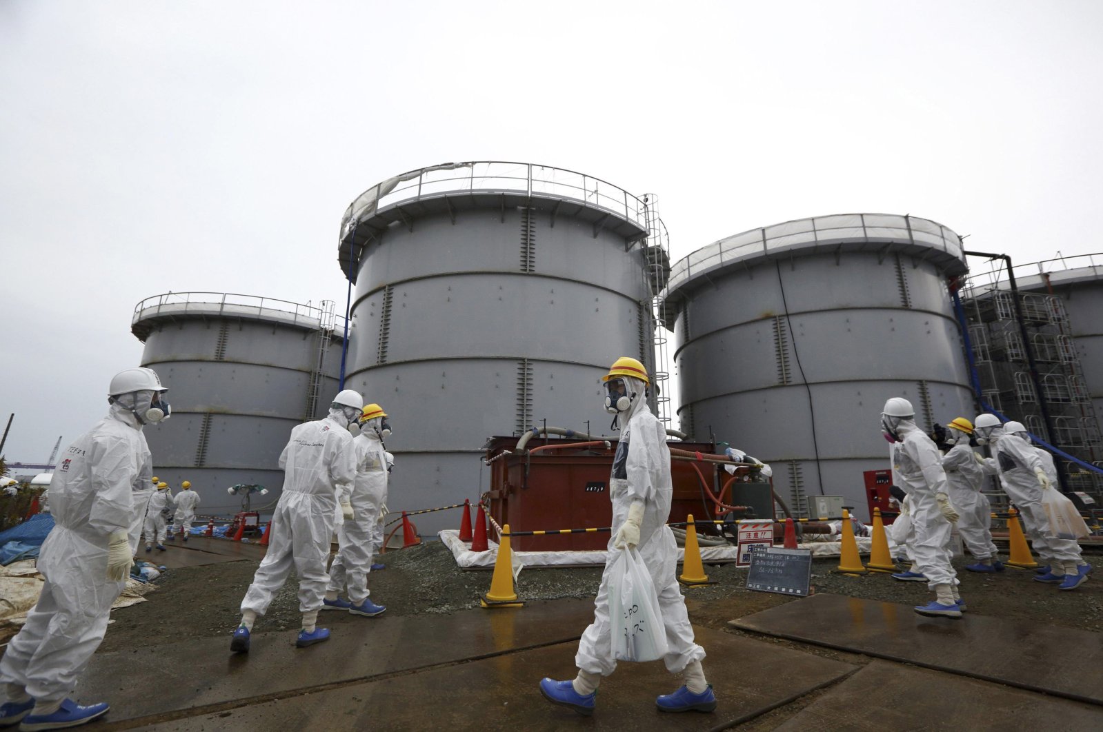 Members of the media and Tokyo Electric Power Co. (TEPCO) employees wearing protective suits and masks walk past storage tanks for radioactive water in the H4 area at the tsunami-crippled TEPCO Fukushima Daiichi nuclear power plant in Fukushima prefecture, Nov. 7, 2013. (Reuters Photo)