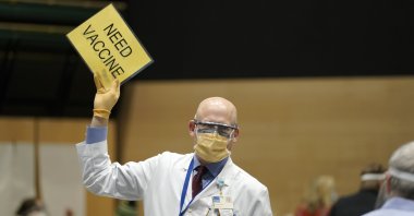 Dr. John Corman, the chief clinical officer for Virginia Mason Franciscan Health, holds a sign that reads "Need Vaccine" to signal workers to bring him more doses of the Pfizer vaccine for COVID-19 in Seattle, Washington state, U.S., Jan. 24, 2021. (AP Photo)