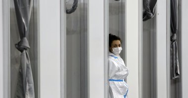 A medical worker wearing protective gear waits for people to receive the COVID-19 vaccine, at Belgrade Fair makeshift vaccination center in Belgrade, Serbia, Feb. 9, 2021. (AP Photo)