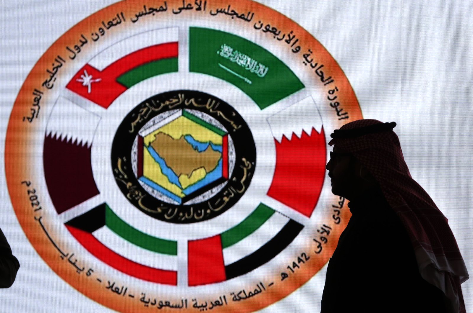 A Saudi television anchor stands in front of the logo of the 41st Gulf Cooperation Council (GCC) at the media center in at Al Ula, Saudi Arabia, Tuesday, Jan. 5, 2021.  (AP Photo)