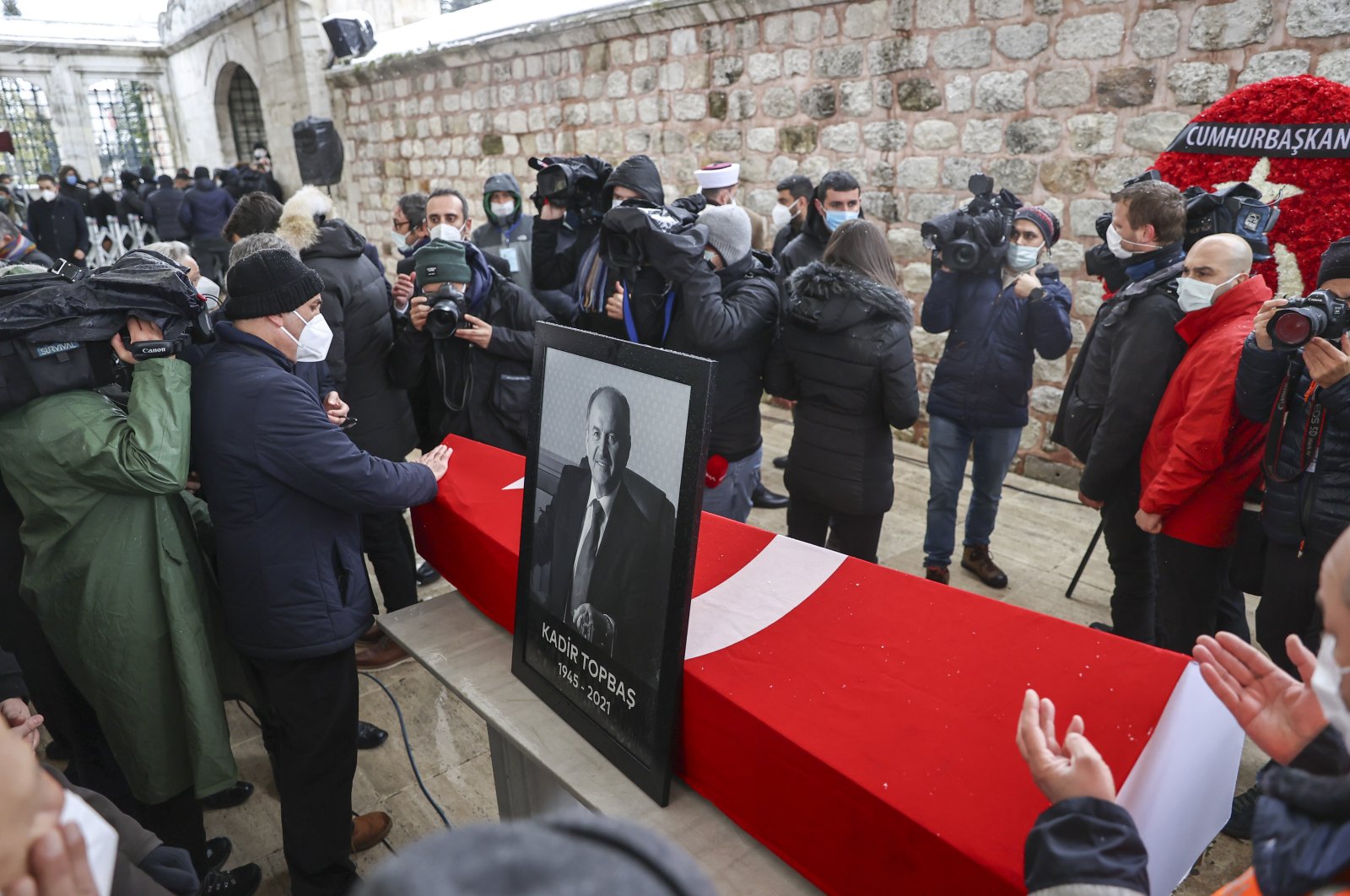 People pray by the coffin of Kadir Topbaş, next to which a photo of the late mayor was placed, in Istanbul, Turkey, Feb. 14, 2021. (AA PHOTO)