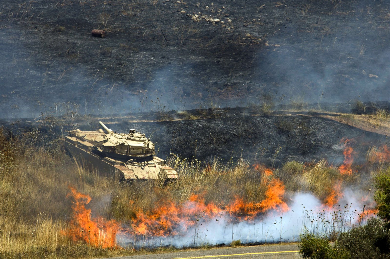 A picture shows an Israeli army tank near flames after mortar fire from inside war-torn Syria hit the Israeli-occupied Golan Heights on July 15, 2013. (AFP Photo)