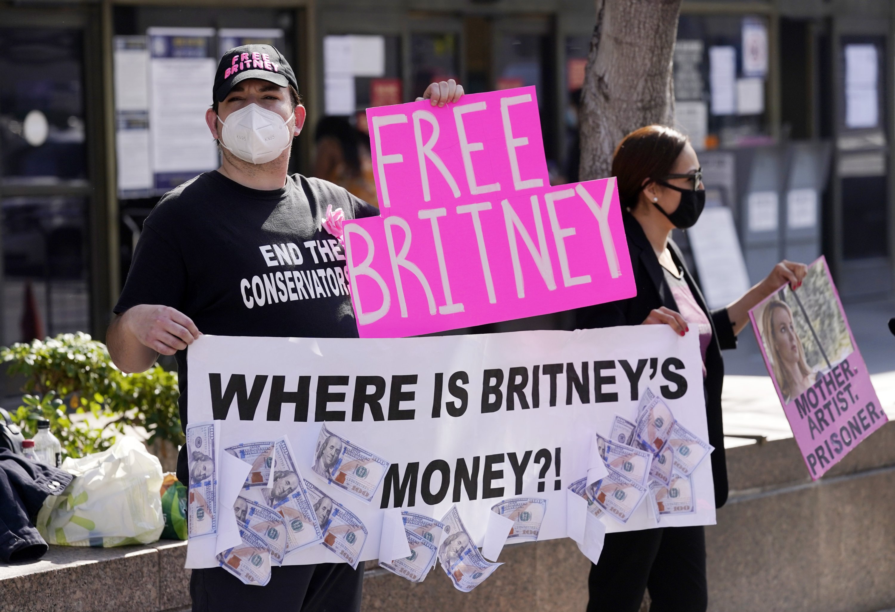Britney Spears supporters Dustin Strand (L) and Kiki Norberto, both of Phoenix, hold signs outside a court hearing concerning the pop singer