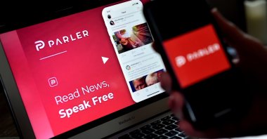 An illustration picture shows the social media application logo from Parler displayed on a smartphone with its website in the background in Arlington, Virginia, July 1, 2020. (AFP Photo)