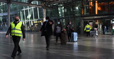 Passengers are escorted to a coach at Heathrow Airport to be driven to a mandatory hotel quarantine in west London on February 15, 2021. (AFP Photo)