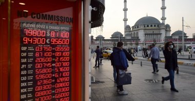 People stand outside an exchange office in the landmark Taksim Square, in Istanbul, Turkey, Oct. 26, 2020. (AP Photo)