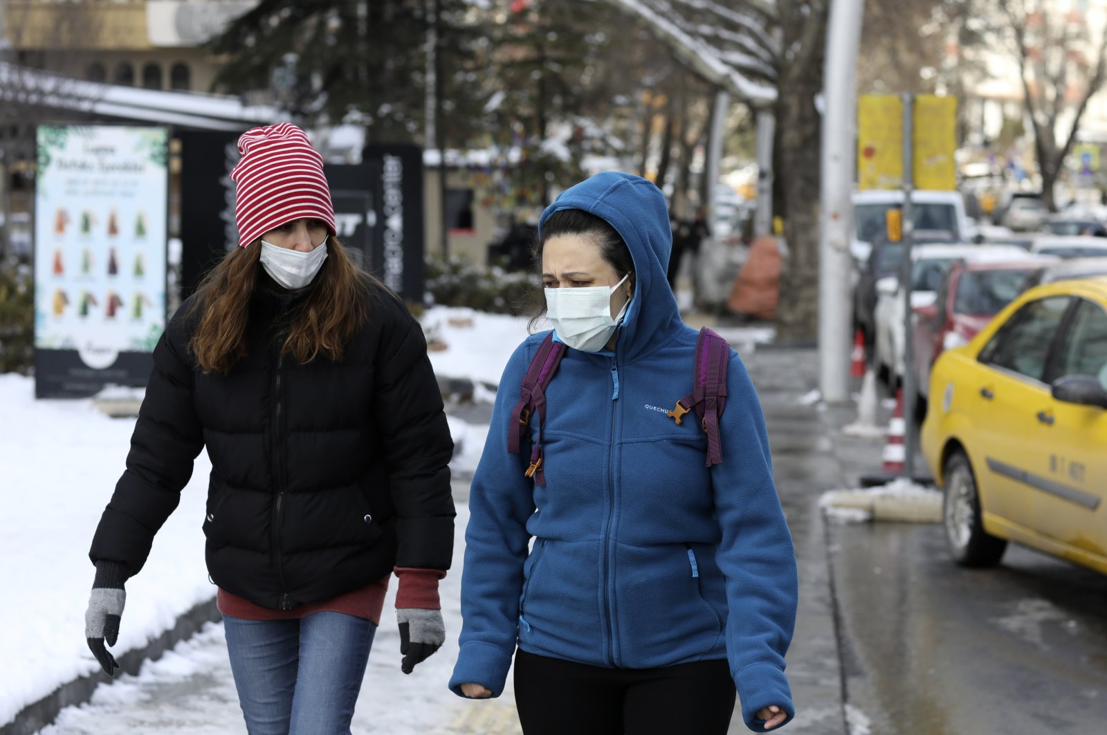 Women wearing masks walk along a busy street, in Ankara, Turkey, Feb. 17, 2021. (AP Photo)