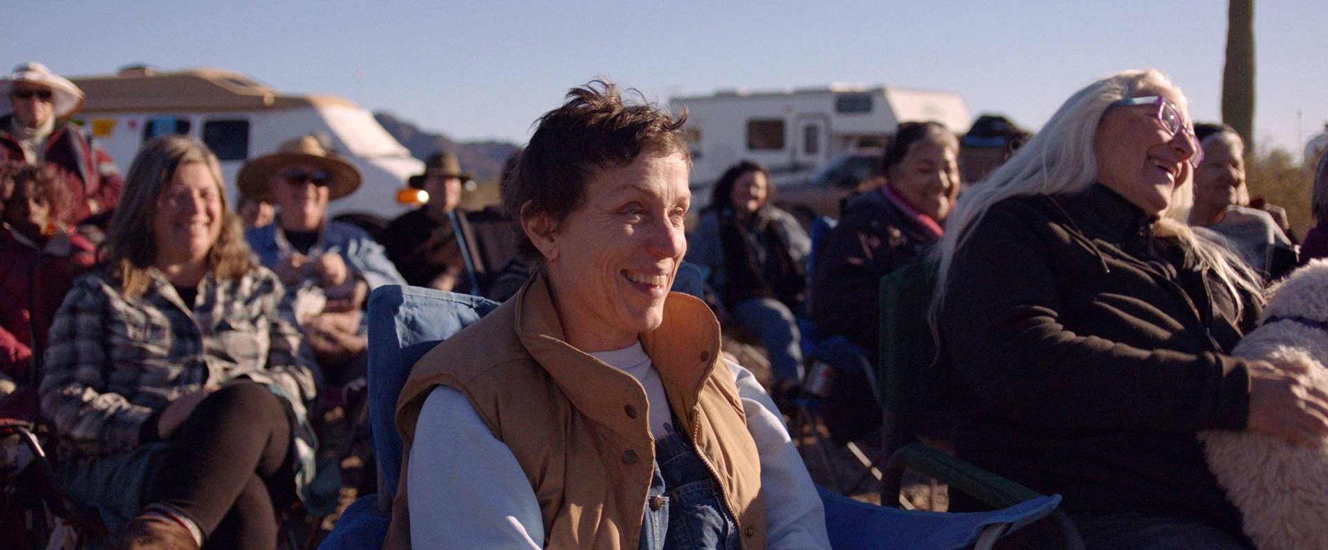 A still image from the film “Nomadland” shows Frances McDormand surrounded by a group of people. (Searchlight Pictures via AP)