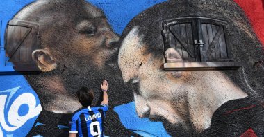 An Inter supporter touches a mural near the Giuseppe Meazza Stadium, depicting Inter Milan's Romelu Lukaku (L) and AC Milan's Zlatan Ibrahimovic during an Italian Cup match, in Milan, Italy, Feb. 15, 2021. (EPA Photo)
