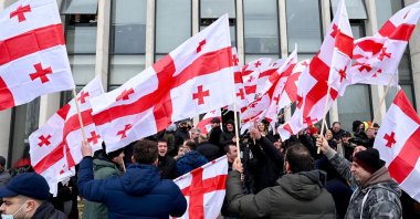 Georgian opposition supporters wave national flags while reacting to the announcement of Prime Minister Giorgi Gakharia's resignation in front of the United National Movement (UNM) headquarters in Tbilisi, Georgia, Feb. 18, 2021. (AFP Photo)