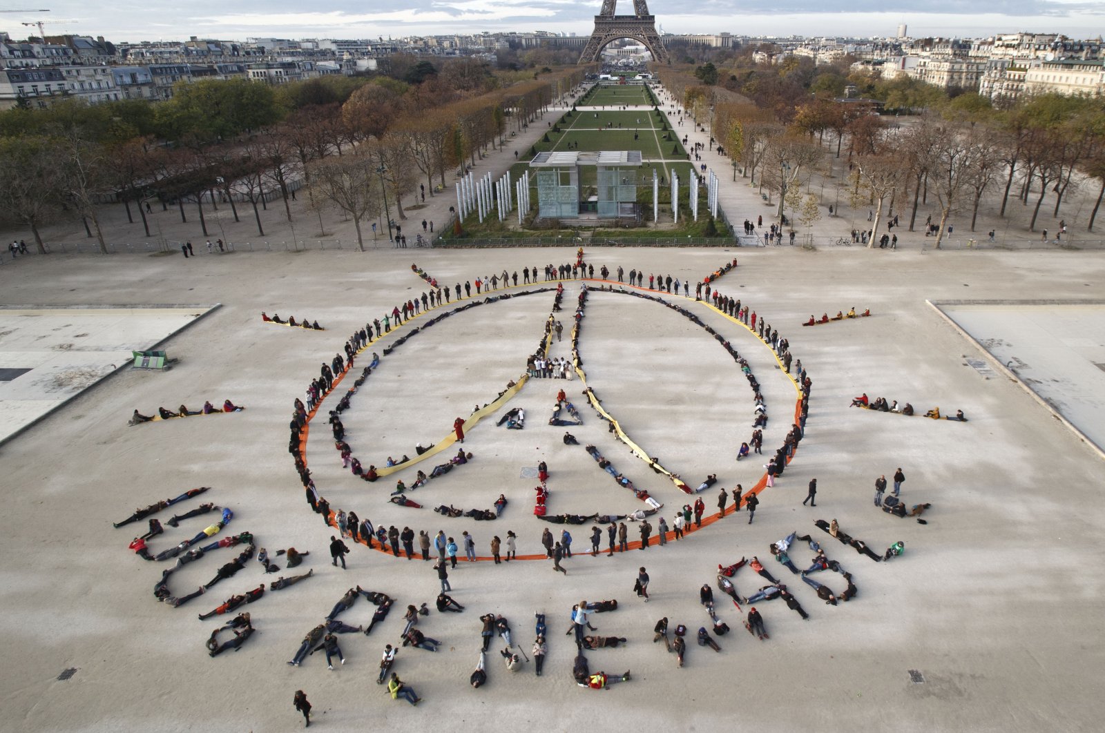 Environmentalist activists form a human chain representing the peace sign and the spelling out "100% renewable," on the side line of the COP21, United Nations Climate Change Conference near the Eiffel Tower in Paris, France, Dec. 6, 2015. (AP Photo)